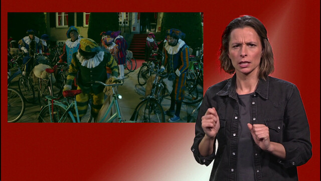 Pieten staan bij hun fiets. Naast het scherm staat de gebarentolk.